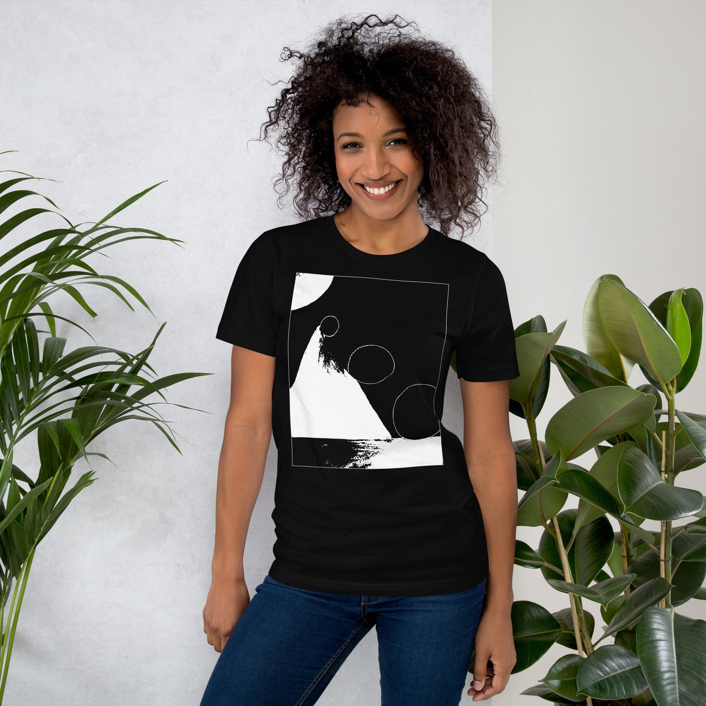 Woman wearing black cotton graphic t-shirt with white abstract pyramid artwork in a thin white square on front