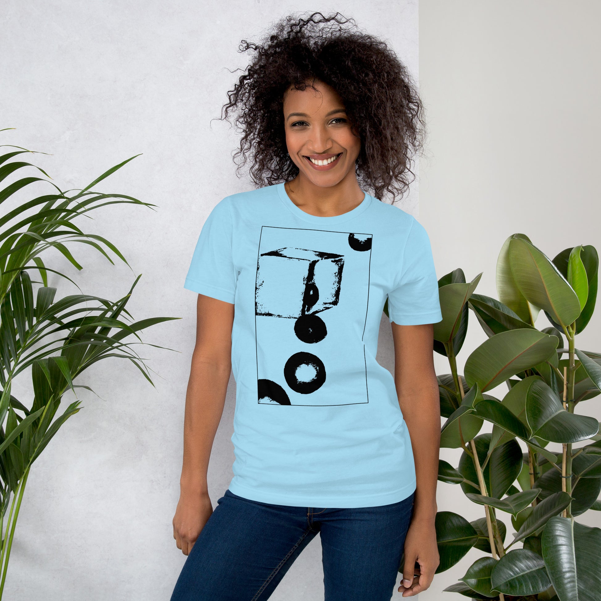 Woman wearing blue cotton graphic t-shirt with black abstract cube and spheres artwork in a thin black square on front