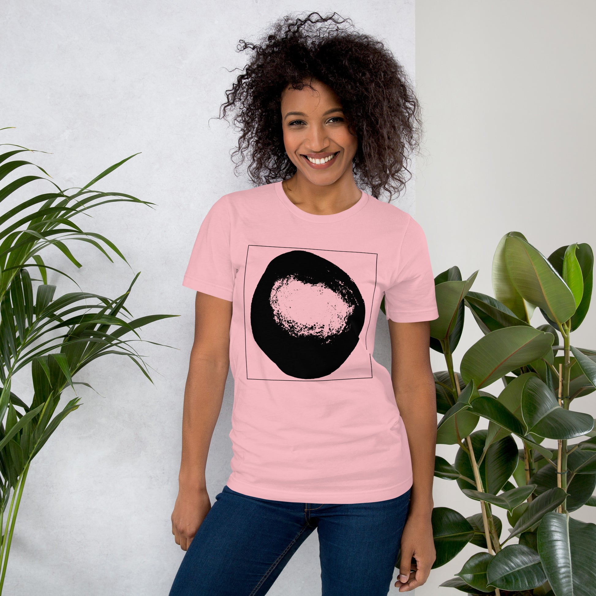 Woman wearing a coral cotton graphic t-shirt with black abstract dome artwork in a thin black square on front